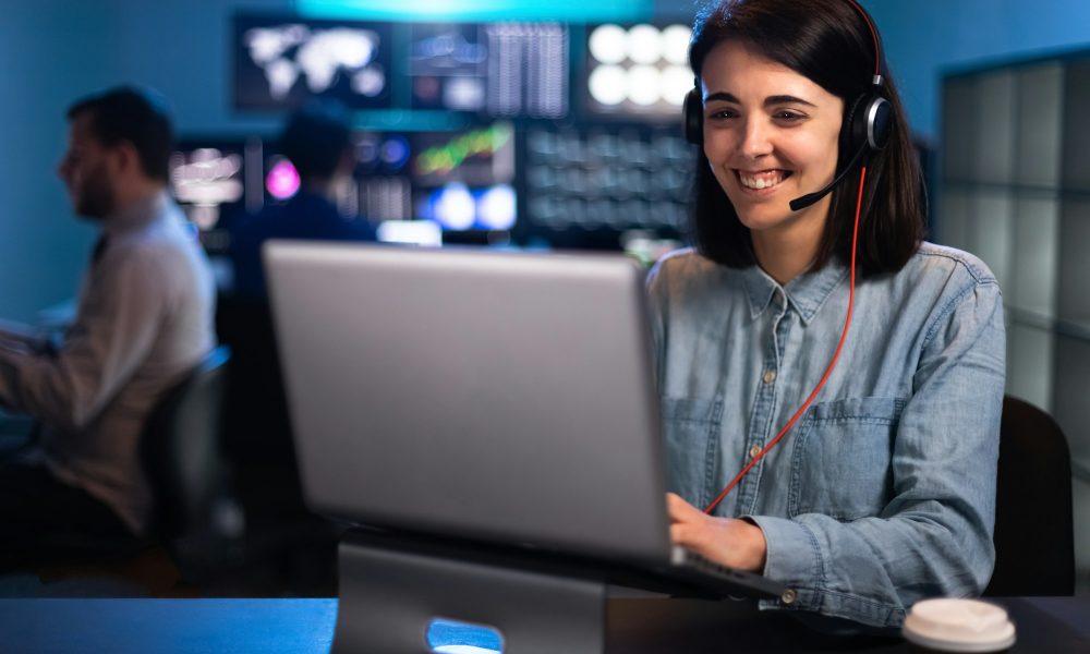 Happy young woman working with laptop in stock market trading analyst office. Costumer service call.